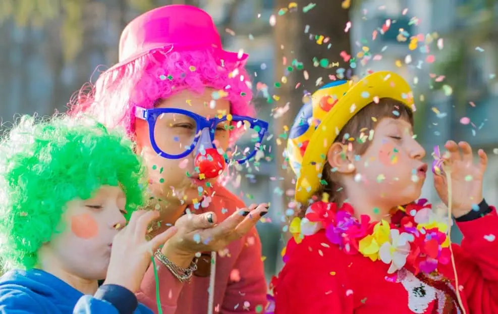 Des enfants déguisés s'amusent et soufflent sur des confettis